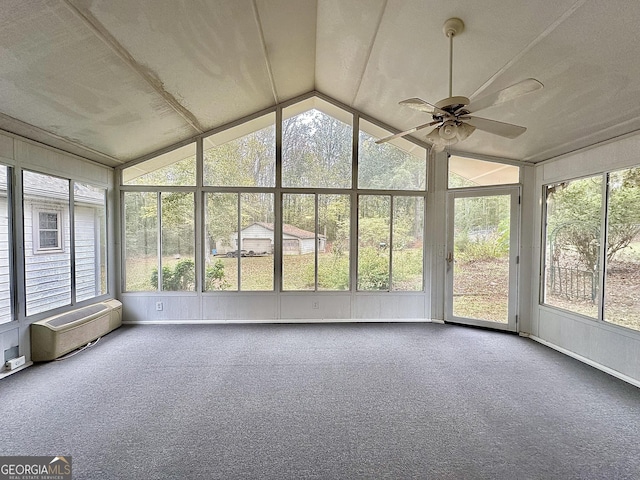 unfurnished sunroom featuring vaulted ceiling, a healthy amount of sunlight, a wall mounted air conditioner, and ceiling fan