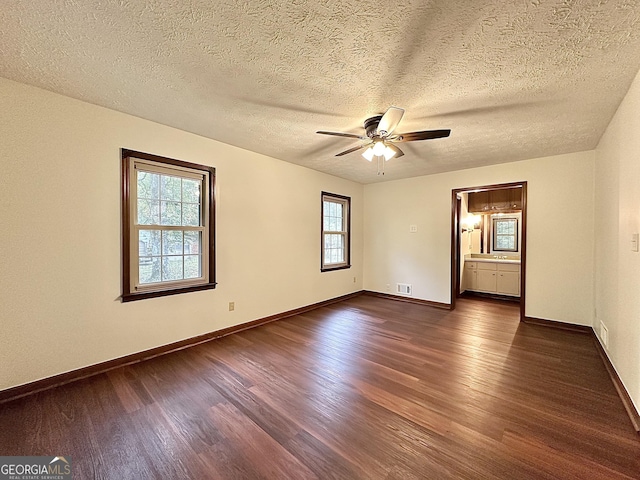 empty room with a textured ceiling, dark wood-type flooring, and ceiling fan