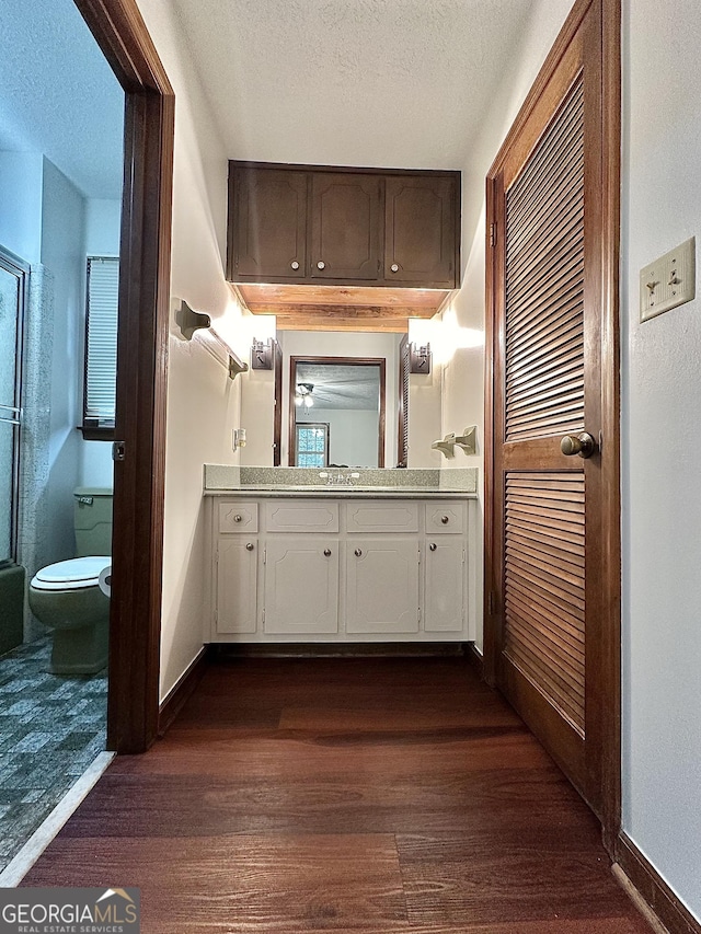 bathroom with vanity, a textured ceiling, wood-type flooring, and toilet