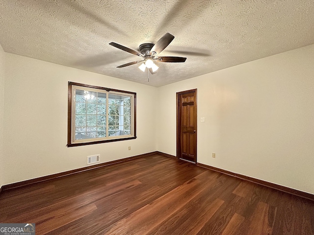 spare room featuring dark wood-type flooring, a textured ceiling, and ceiling fan