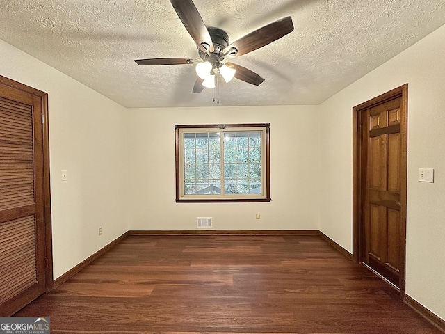 empty room featuring ceiling fan, dark hardwood / wood-style floors, and a textured ceiling