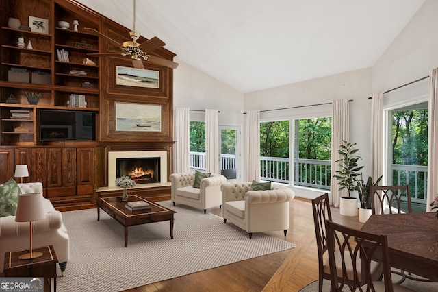 living room featuring plenty of natural light, a fireplace, high vaulted ceiling, and light wood-type flooring