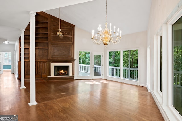 unfurnished living room featuring hardwood / wood-style flooring, a large fireplace, a wealth of natural light, and decorative columns