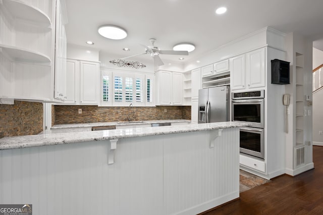 kitchen with white cabinetry, a kitchen breakfast bar, light stone counters, kitchen peninsula, and stainless steel appliances