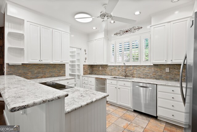 kitchen featuring sink, stainless steel appliances, light stone counters, white cabinets, and kitchen peninsula