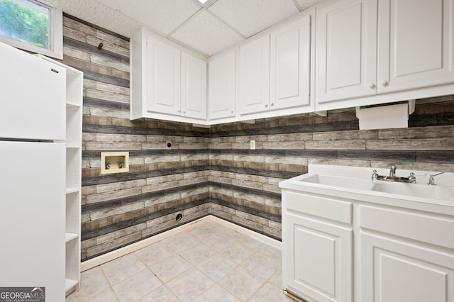 clothes washing area featuring sink, hookup for a washing machine, light tile patterned floors, and wood walls