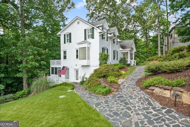 view of front of home with a balcony and a front lawn