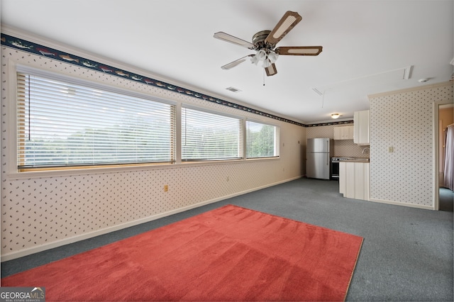 unfurnished living room with ceiling fan and dark carpet