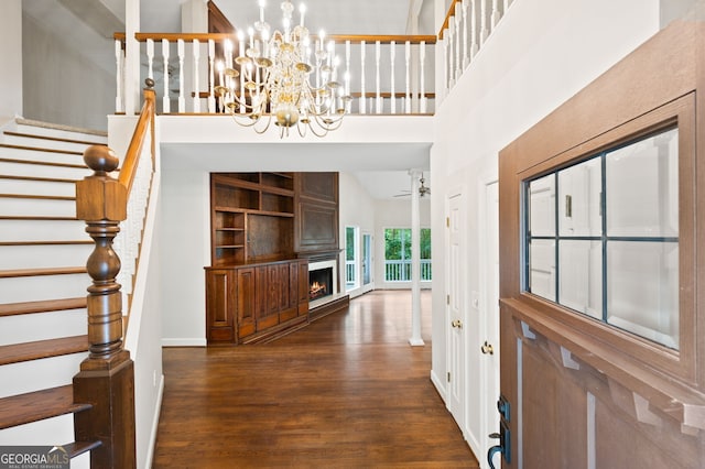 foyer featuring a towering ceiling, dark hardwood / wood-style flooring, and ceiling fan with notable chandelier