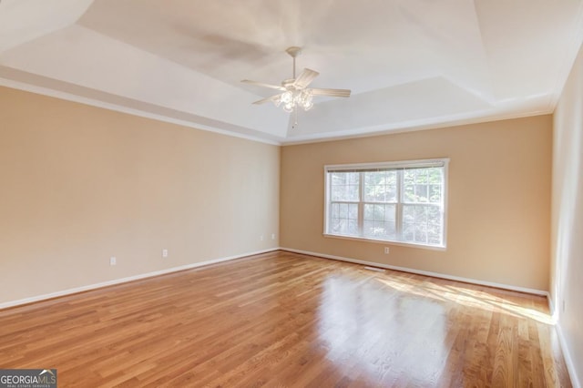 unfurnished room with a tray ceiling, ornamental molding, light hardwood / wood-style floors, and ceiling fan