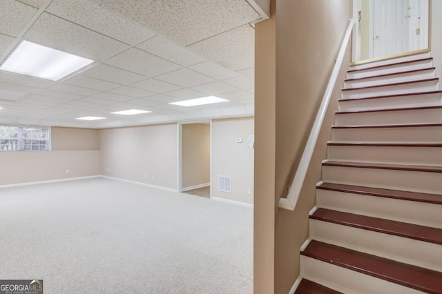 basement with a paneled ceiling and carpet flooring