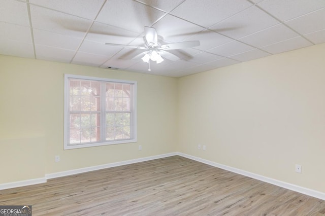 spare room with ceiling fan, light wood-type flooring, and a drop ceiling