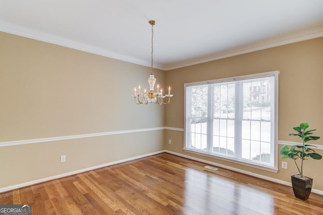 unfurnished room featuring ornamental molding, hardwood / wood-style floors, and an inviting chandelier