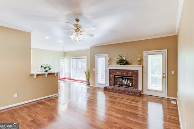 unfurnished living room with crown molding, a fireplace, light hardwood / wood-style floors, and ceiling fan