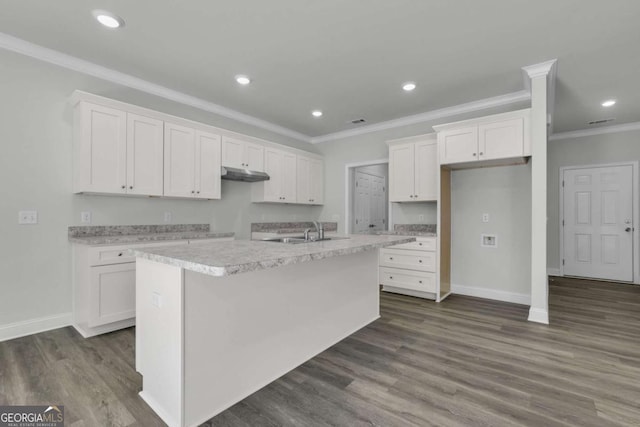 kitchen featuring white cabinetry, crown molding, an island with sink, and dark hardwood / wood-style flooring