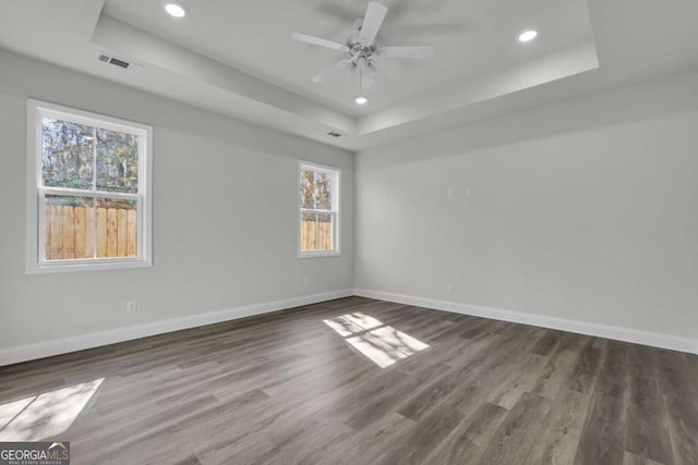 unfurnished room with ceiling fan, dark hardwood / wood-style flooring, and a raised ceiling