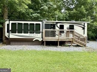 back of house with a deck and a lawn