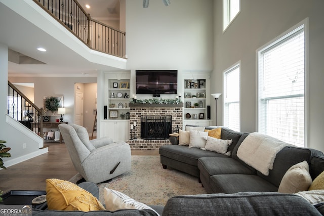 living room with a high ceiling, crown molding, a brick fireplace, and dark wood-type flooring