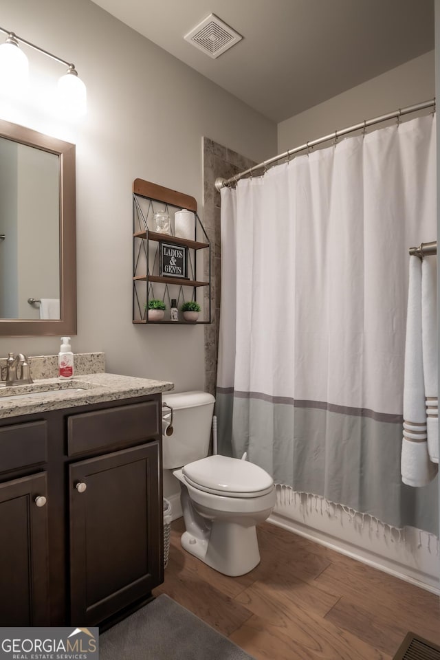 bathroom featuring walk in shower, wood-type flooring, toilet, and vanity