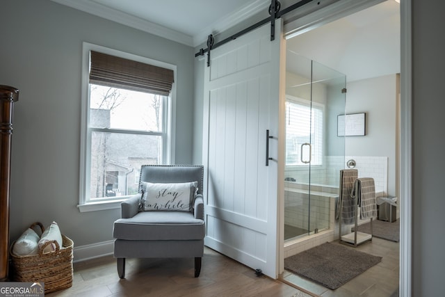 living area featuring hardwood / wood-style floors, ornamental molding, a barn door, and a wealth of natural light