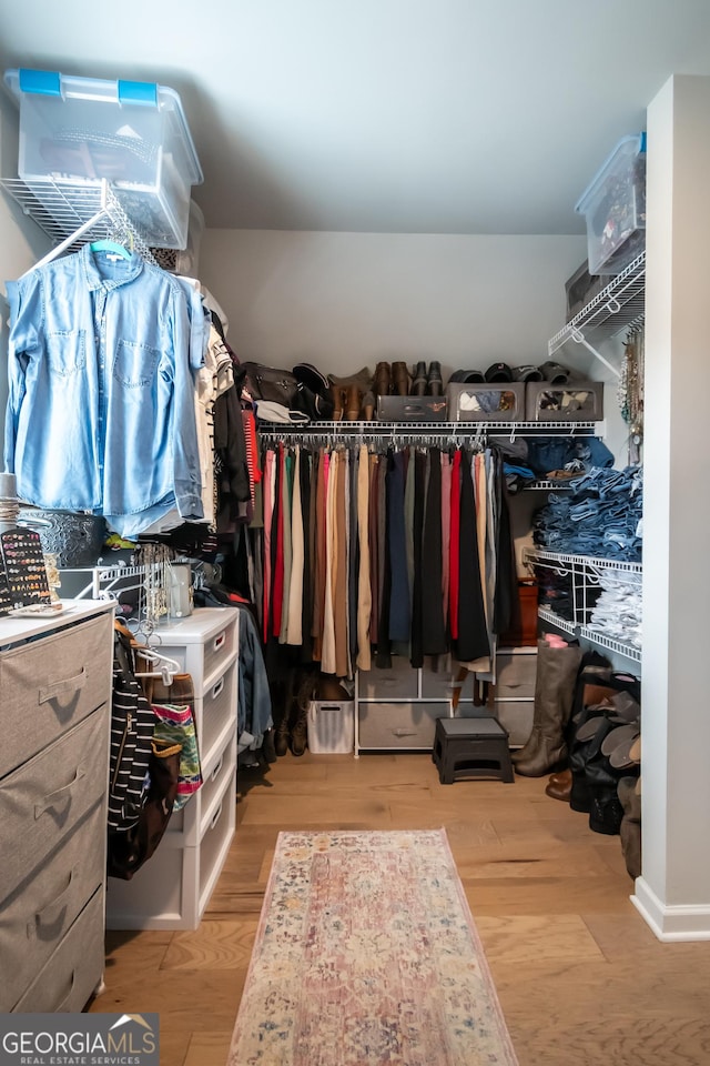 walk in closet with light hardwood / wood-style floors