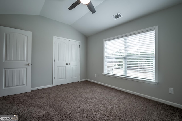 unfurnished bedroom featuring lofted ceiling, a closet, ceiling fan, and carpet flooring