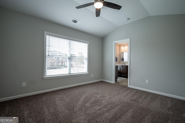 unfurnished bedroom featuring ceiling fan, lofted ceiling, ensuite bathroom, and carpet