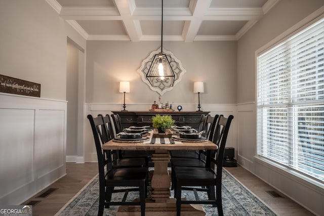 dining space featuring beamed ceiling, wood-type flooring, coffered ceiling, and crown molding