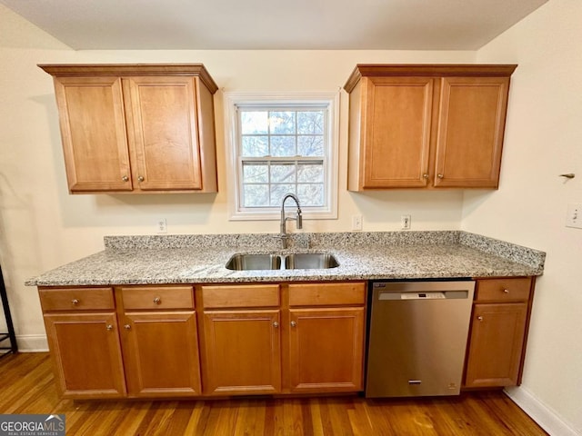 kitchen featuring sink, wood-type flooring, stainless steel dishwasher, and light stone countertops