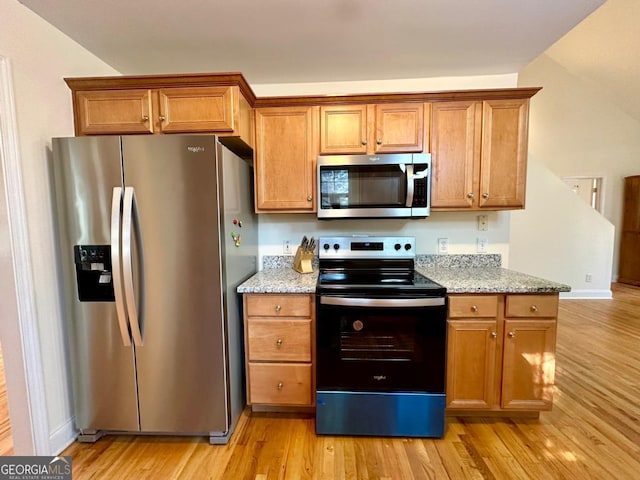 kitchen featuring light stone countertops, appliances with stainless steel finishes, and light hardwood / wood-style flooring