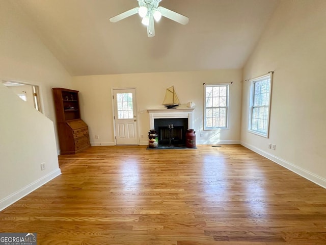 unfurnished living room with ceiling fan, lofted ceiling, a healthy amount of sunlight, and light wood-type flooring