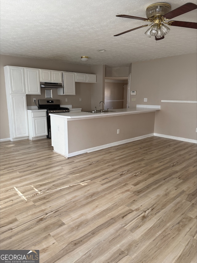 kitchen with white cabinetry, sink, stainless steel gas range, and light hardwood / wood-style floors