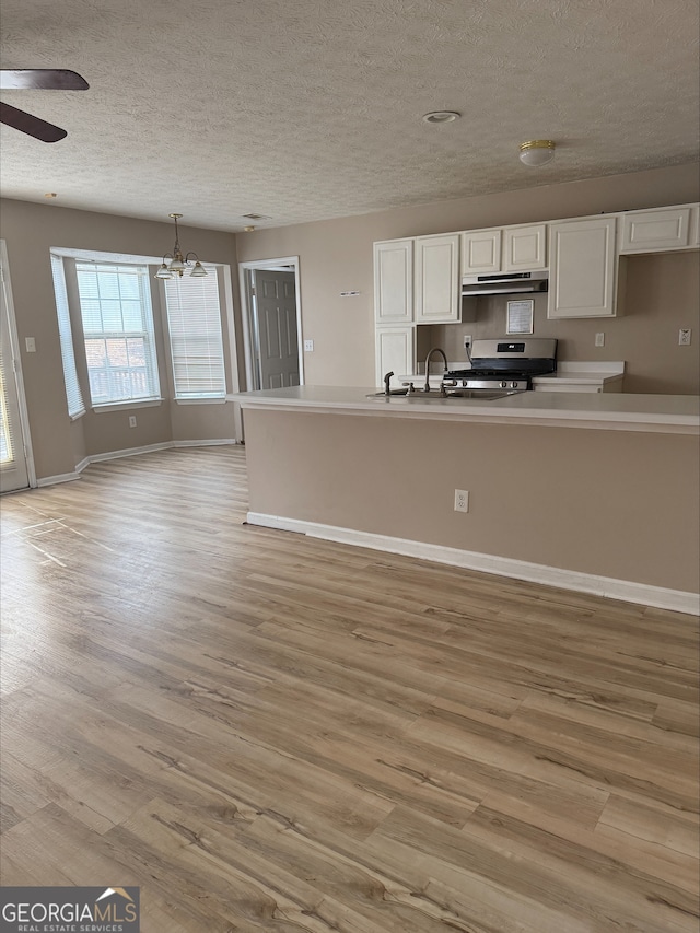 kitchen featuring pendant lighting, stainless steel range, white cabinets, and light wood-type flooring