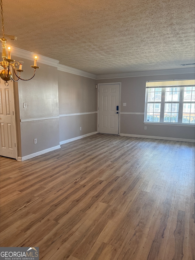 unfurnished living room with ornamental molding, a chandelier, hardwood / wood-style floors, and a textured ceiling