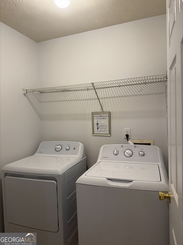 laundry room with separate washer and dryer and a textured ceiling