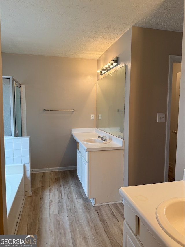 bathroom with a bath, vanity, hardwood / wood-style floors, and a textured ceiling