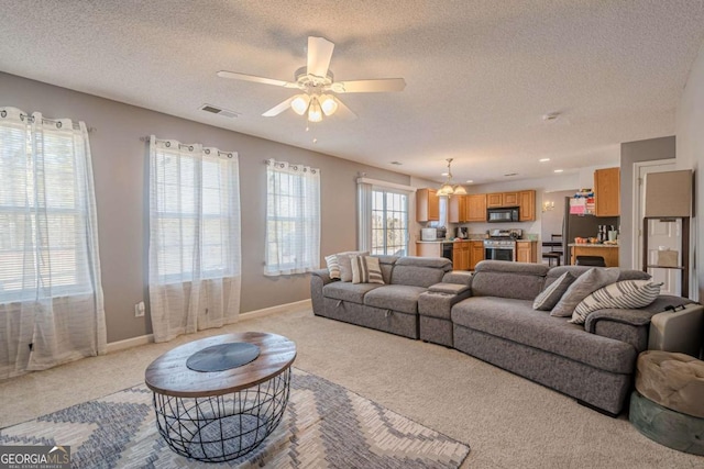 carpeted living room with ceiling fan and a textured ceiling