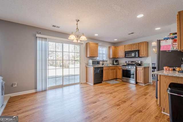 kitchen with hanging light fixtures, a notable chandelier, black appliances, and light wood-type flooring