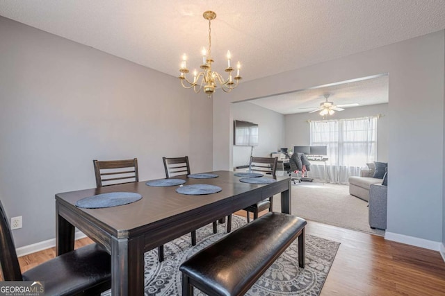 dining area featuring hardwood / wood-style flooring, ceiling fan with notable chandelier, and a textured ceiling