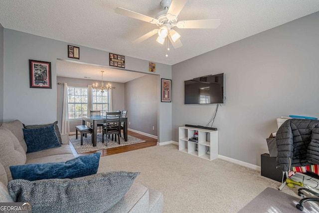 carpeted living room featuring ceiling fan with notable chandelier and a textured ceiling