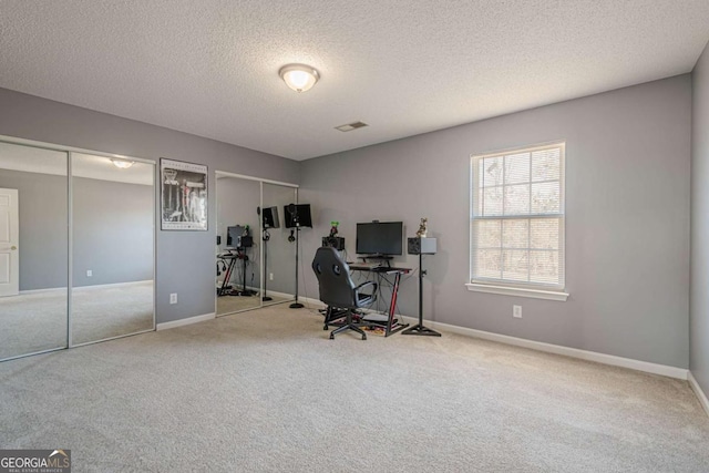 carpeted office featuring a textured ceiling