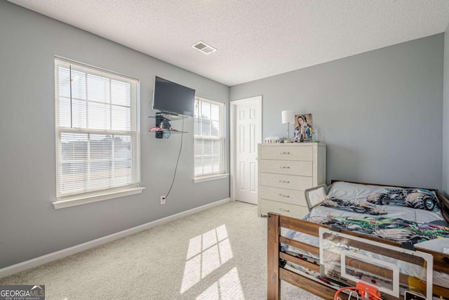 bedroom featuring light colored carpet and a textured ceiling