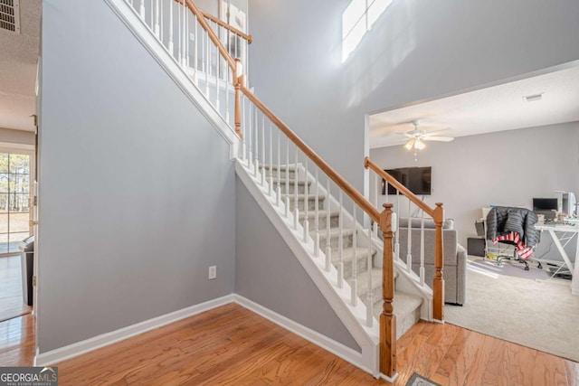 stairs featuring hardwood / wood-style floors, ceiling fan, and a high ceiling