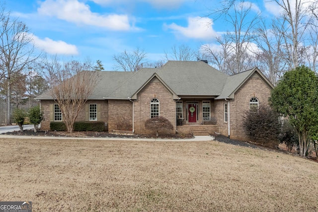 single story home with brick siding, a front lawn, and a shingled roof