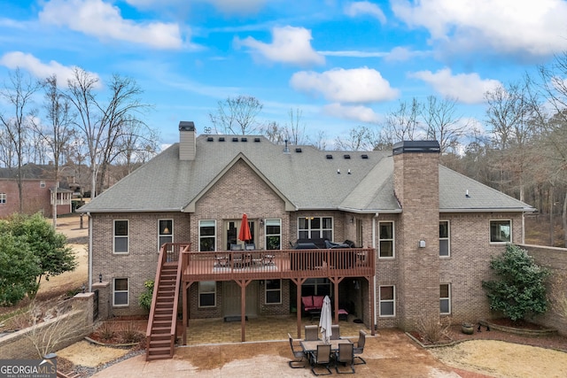 rear view of property featuring a deck, brick siding, stairs, a chimney, and a patio area