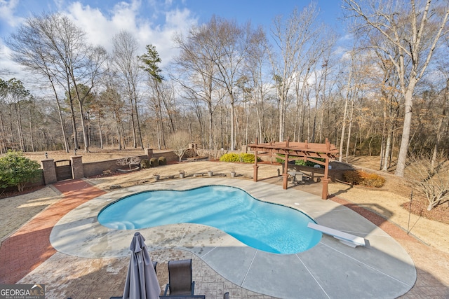 pool featuring a patio, a view of trees, and a diving board