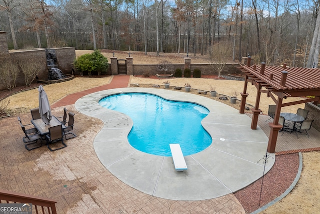 outdoor pool with a patio and a diving board
