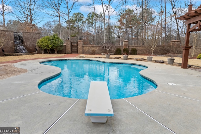 outdoor pool with a diving board, a patio area, and fence