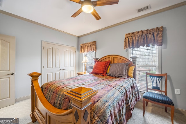 carpeted bedroom featuring ornamental molding, a closet, and ceiling fan