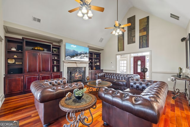 living room with ceiling fan, high vaulted ceiling, dark wood-type flooring, and a fireplace